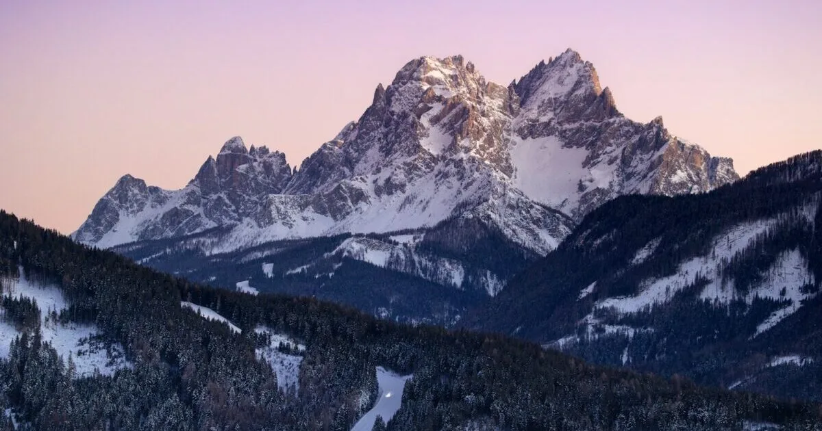 Snow-capped mountains peak against a colorful sunset.