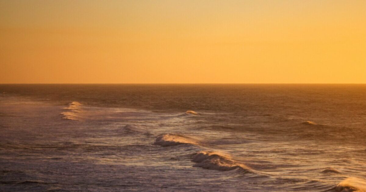 The sun sets over the ocean.